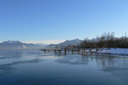 Zugefrorener See mit Bergen im Hintergrund